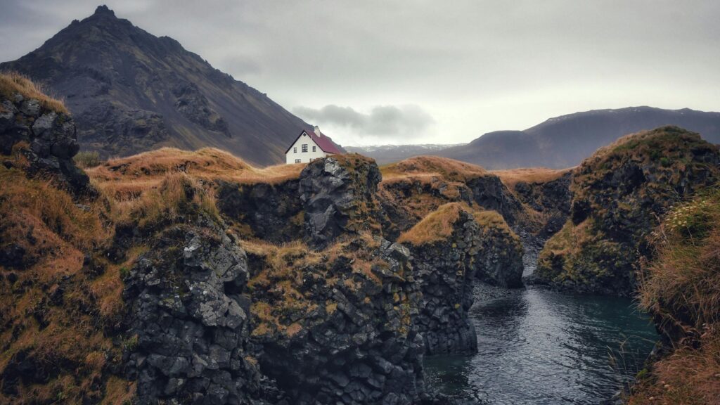 Visão aérea de uma ilha rochosa isolada cercada por um mar agitado sob um céu nublado, ilustrando o cenário de E Não Sobrou Nenhum.